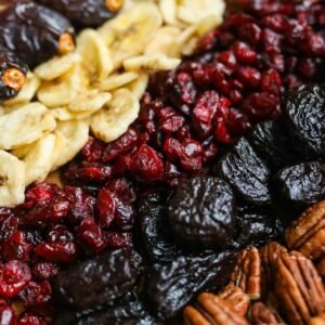 Vibrant mix of dried fruits and nuts on a wooden tray, perfect for healthy snacking.